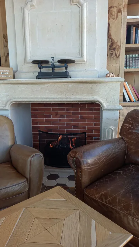 Leather armchairs by lit fireplace in cozy Paradores castle lounge