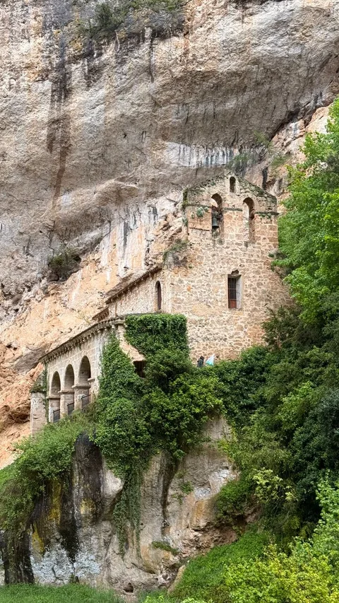 Discover a historical stone hermitage nestled in a stunning Spanish cliffside landscape.