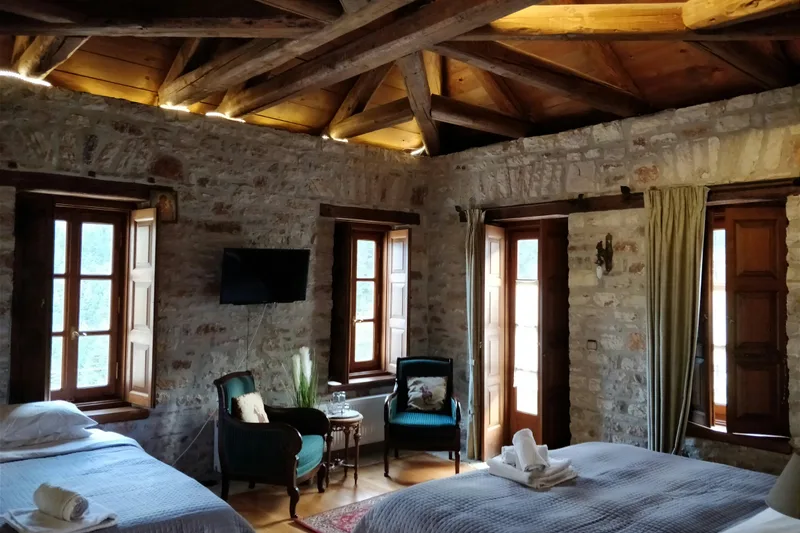 Stone-walled medieval castle hotel bedroom with wooden beams and twin beds