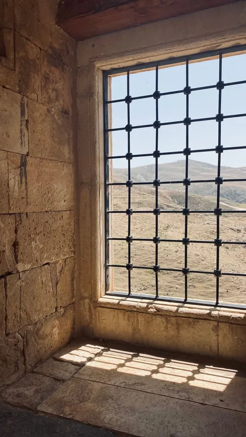 Historic castle stone window seat with barred window overlooking hills