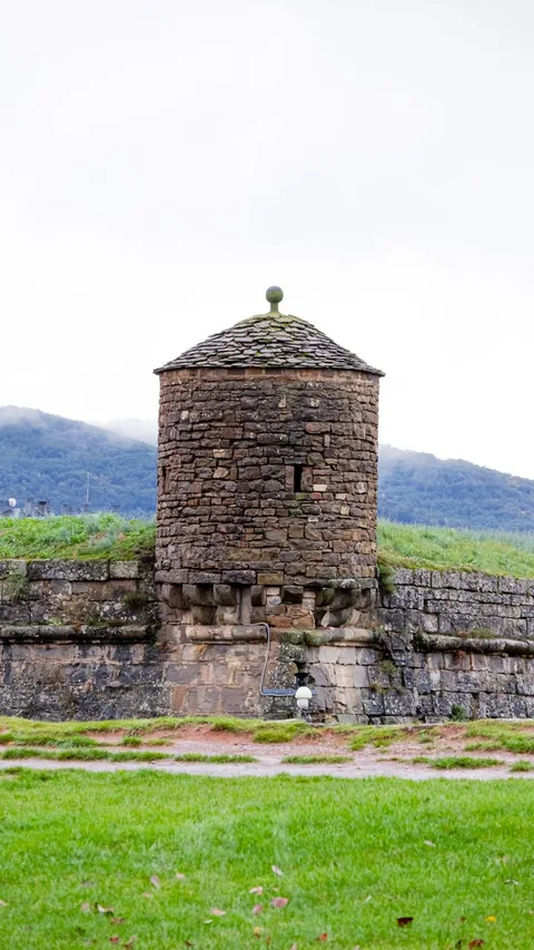 A picturesque stone tower surrounded by lush greenery in a rural setting.