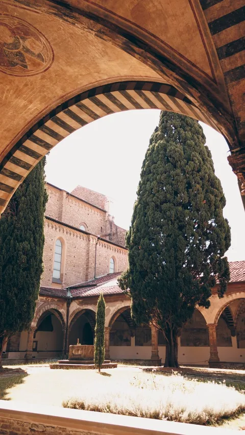 Cloister arches of Parador de Granada with tall cypresses and fountain