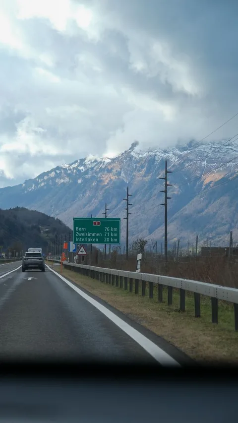 Snow-capped mountains visible from a highway in Switzerland, capturing a serene drive.