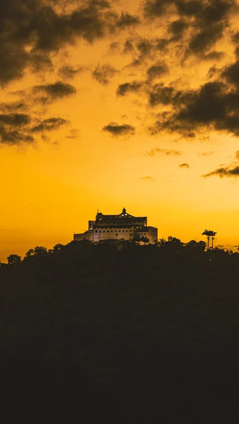 Parador castle on hilltop silhouetted against sunset sky in Spain