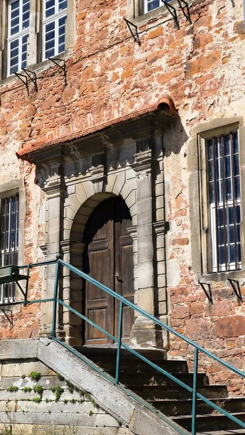 A detailed view of a historic stone building entrance with stairs and metal railings.
