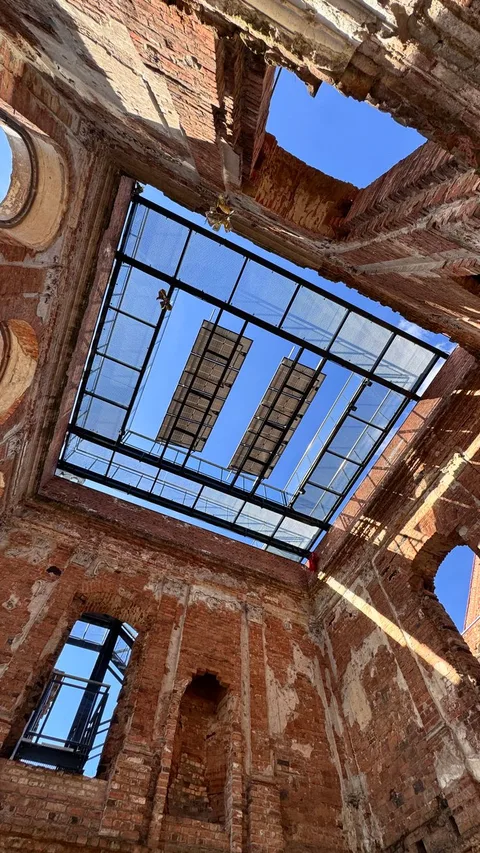 View from inside a historic brick ruin with an open roof, under sunny sky.